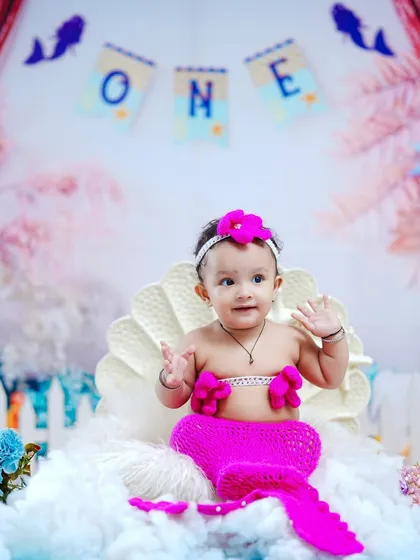 A happy wave from our adorable little mermaid, dressed in a bright pink knitted tail and top.
