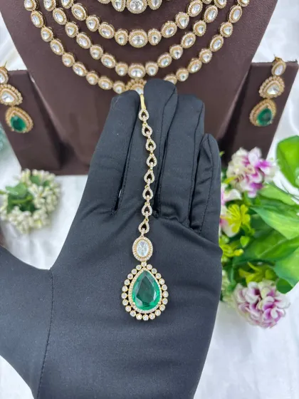 Our multi-layered Rani Haar sets are a bestseller. This piece showcases six layers of uncut Polki-style stones with a stunning emerald green pendant and matching earrings, offering a truly royal look for weddings and grand occasions.
