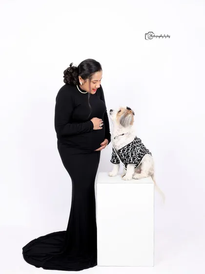 A sweet studio portrait of a mother-to-be sharing a moment with her pet.