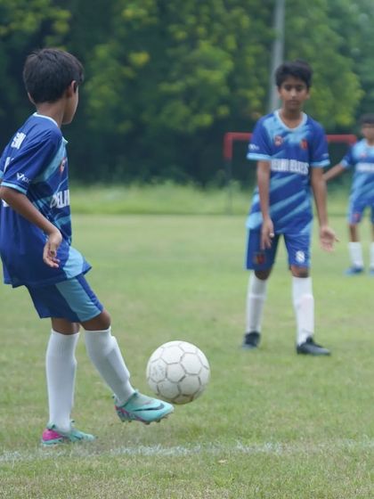 A young player focused on his first touch during a match, preparing to control the ball and make his next move.