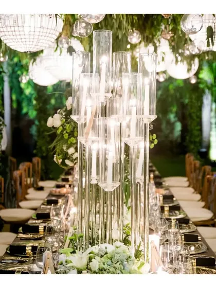 A dramatic centerpiece composed of tall glass cylinders with floating candles. This striking decor element, combined with our catering, elevates the entire dining room into a space of modern elegance.