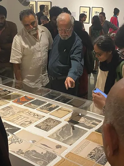Artist Gulammohammed Sheikh explaining the details of his journals and book covers to an engaged audience during the preview of his 'Hand Prints' retrospective.