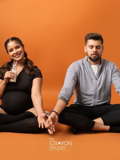 Finding balance together. This meditative pose, with a playful twist as she sips her drink, is a fun way to show their partnership during the pregnancy.