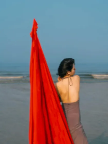 Using a simple prop like a piece of red fabric can add a dramatic and artistic element to a beach shoot, creating a beautiful flow of color.