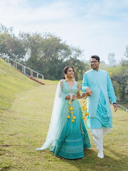 A happy couple walking hand-in-hand through the lawns of their Udaipur venue during their Haldi function.