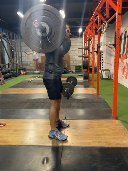 This client is setting up for a drop snatch, with the bar on his back, ready to punch his body down into the squat.
