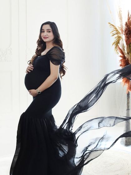 A classic and elegant portrait in a black mermaid-style gown with a flowing train. The bright, airy setting provides a beautiful contrast.