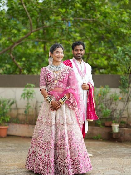 A happy bride and groom moment. She is wearing our pink and white embroidered lehenga, showing how our outfits look in professional wedding photos. We love being a part of your special day.