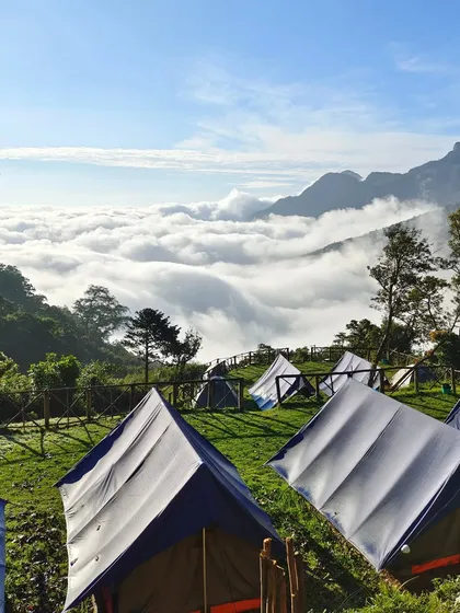 A wide view of the campsite on a clear day, with the tents looking out over the cloud filled valley.