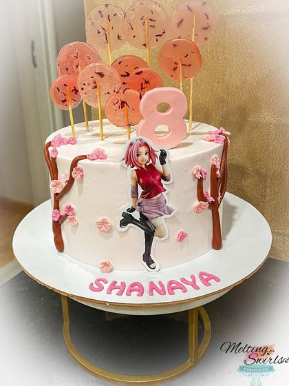This Sakura-themed cake is a beautiful tribute to the Japanese anime, made for a twin's birthday. It features delicate cherry blossoms and isomalt lollipops, creating an elegant and unique design.