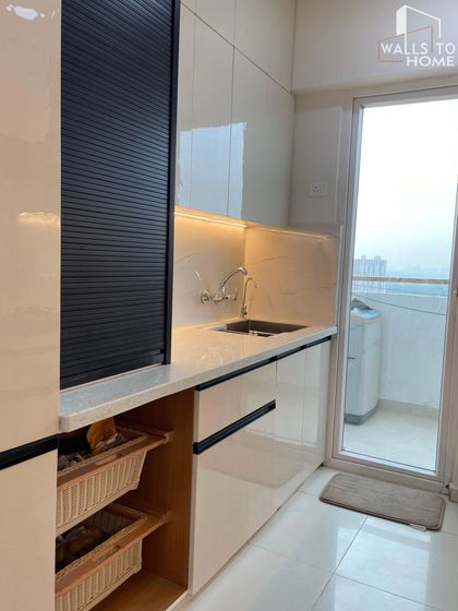 This kitchen features smart storage solutions, including wicker baskets for vegetables and a rolling shutter to hide appliances. The design keeps the countertop organized and clutter-free.