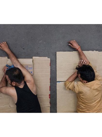 03:02am: Travelers sleep on cardboard mats on a railway platform, a common sight during train delays. This overhead shot provides a poignant, documentary perspective on the realities of travel.