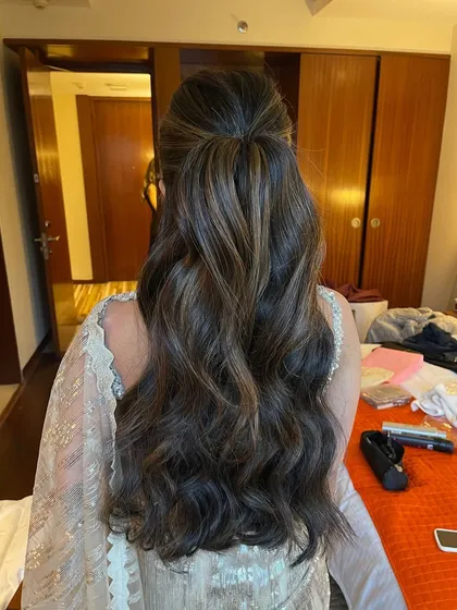A half up, half down hairstyle with a slight puff at the crown for volume. The rest of the hair is styled in soft, flowing waves.