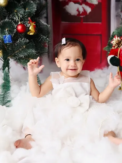 A joyful shot from a Christmas-themed first birthday, with the little girl clapping her hands in excitement.