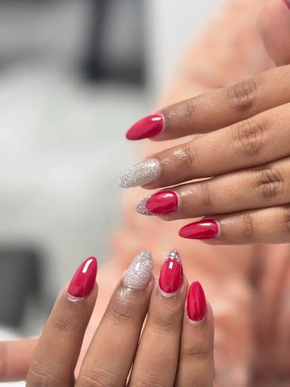 A vibrant red manicure with sparkling silver glitter accents. This set combines a solid color, a full glitter nail, and a glitter-tipped nail for a fun, mixed look.