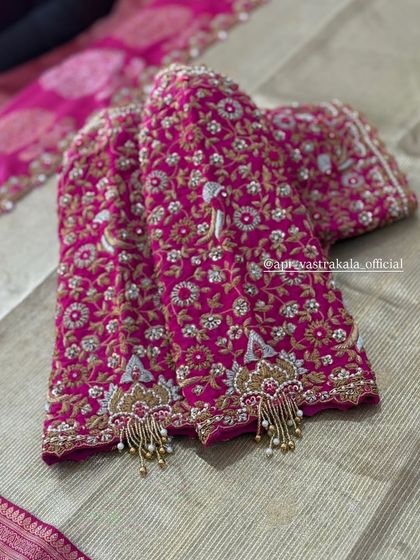 A pink blouse with peacock and floral zardosi work, finished with pearl tassels.