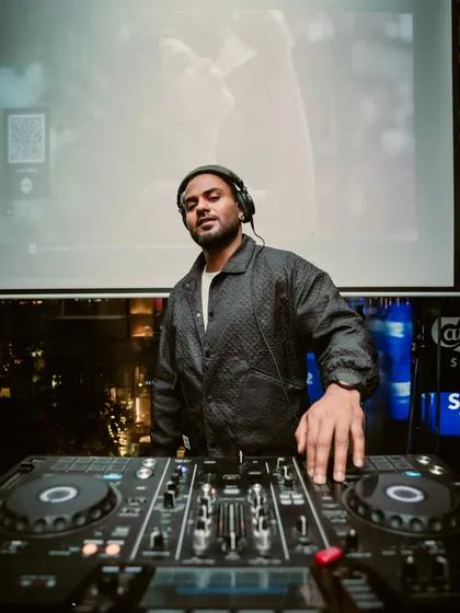 A moment of calm before the crowd arrives. This shot captures me at my console, with the city lights in the background, ready to start the night's musical journey.