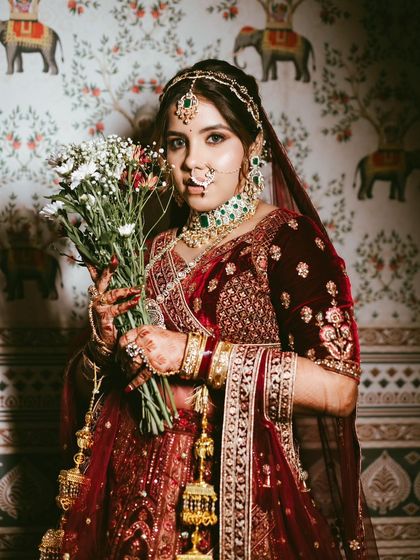 A classic bridal portrait with a bouquet, capturing the timeless elegance of the red lehenga look.