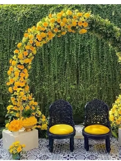 I designed this elegant Haldi ceremony seating with a beautiful arch of fresh yellow marigolds and lush greenery. The two ornate black chairs create a striking contrast, making it a perfect photo spot. I can create this kind of sophisticated outdoor wedding decor at your venue anywhere in the Delhi NCR region.