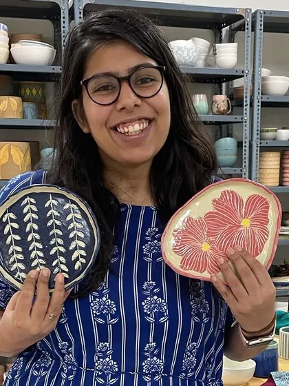 A happy student showing off the two beautiful plates she designed and painted in our one-day workshop. The shelves behind her are filled with inspiration.