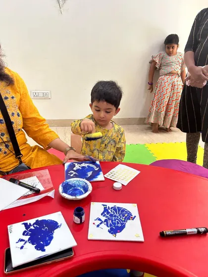 A young artist carefully works on a peacock feather stencil print during our Janmashtami celebration. We combine cultural themes with fun, accessible art projects for all our students.