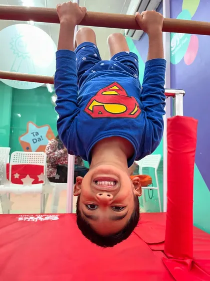 Hanging upside down is a fun way to build core strength and body awareness. This smiling 'superhero' is getting a great workout while seeing the world from a different angle.