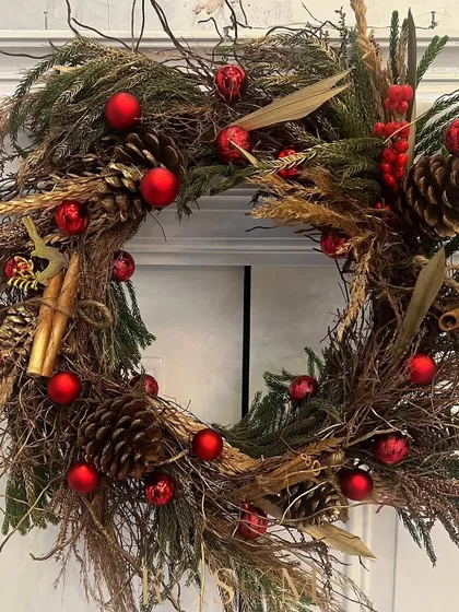 A classic gold-dusted wreath with cinnamon whispers. This design combines wild woody stems, earthy pinecones, and bright red Christmas baubles for a traditional and festive look.
