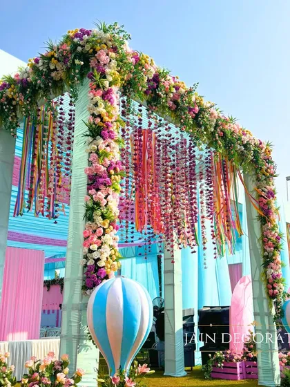 A grand entrance for a carnival event, featuring a floral arch, colorful ribbons, and hot air balloon props. It's a welcome that promises a day of fun and excitement.