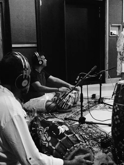 A black and white shot of me singing while the percussionists listen intently. This captures the dynamic of a live recording session, where we all feed off each other's energy.