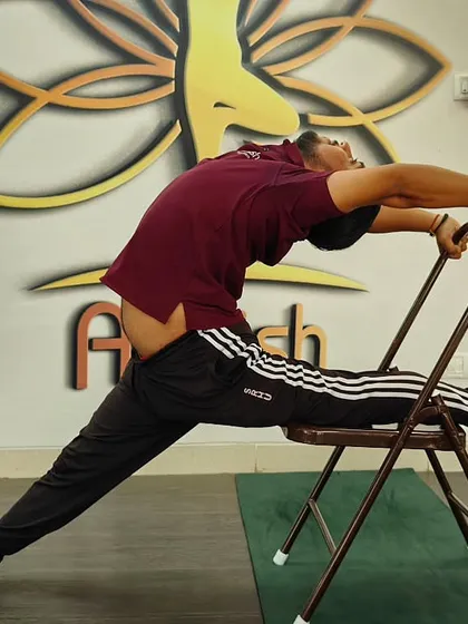 Using a chair for support, this practitioner explores an advanced variation of Hanumanasana (split pose) with a deep backbend.