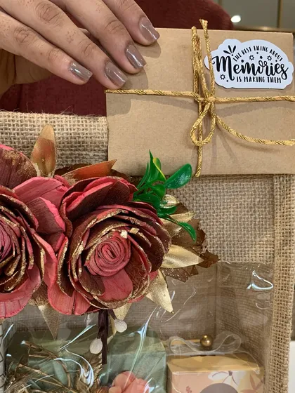 A close-up of the jute bag hamper, showing the "Memories" sticker and the beautiful paper flower decorations. It's all about the personal touches.