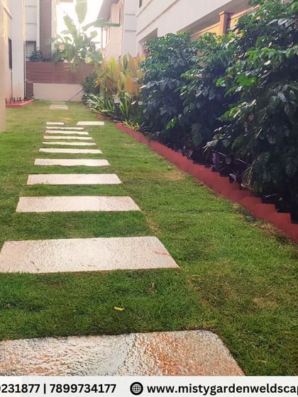 A view down the stepping stone path in the Bommenahalli garden. The stones are perfectly leveled and spaced to create a comfortable and visually pleasing walkway.