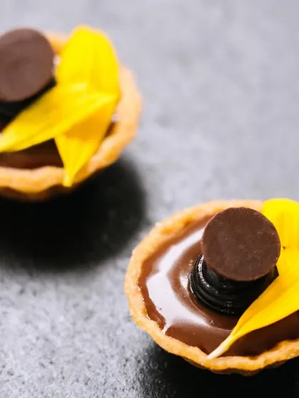 Our mini chocolate tarts decorated with bright yellow flower petals for a festive Holi party. We love adding a touch of color and fun to our desserts.