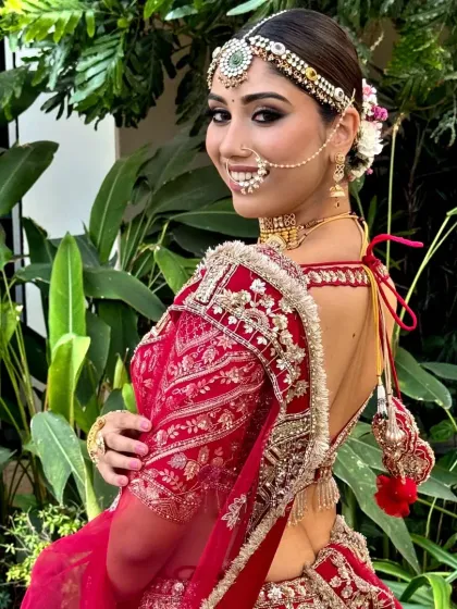 A close-up of a model's bridal look, featuring a neat bun decorated with a garland of fresh, colorful flowers. This hairstyle adds a touch of romance to the traditional look.