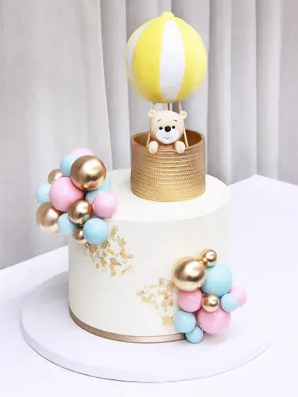 Another beautiful hot air balloon cake for a baby shower, this time with a yellow and white balloon and a sweet teddy bear peeking out of the basket.