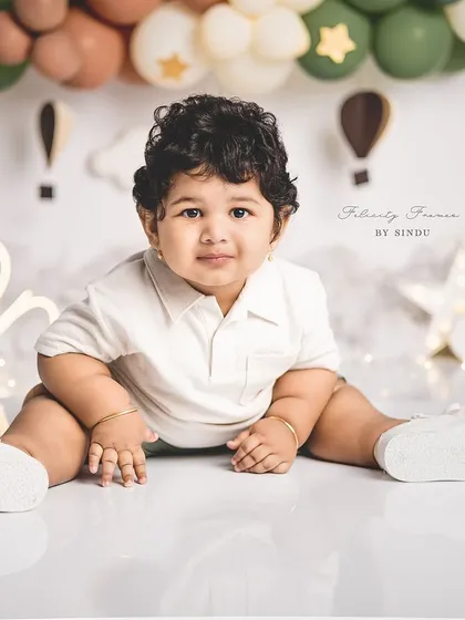 A classic portrait of a one-year-old boy. The simple setup with neutral-colored balloons is perfect for a timeless look.