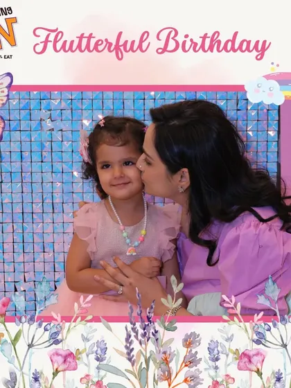 A sweet moment at a butterfly and rainbow-themed birthday bash. A mother's kiss for the birthday girl captures the love and joy of the celebration.