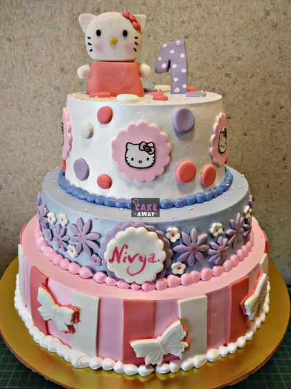 A three-tier Hello Kitty cake perfect for a first birthday. It combines different patterns, colors, and edible character plaques to create a beautiful and memorable design.