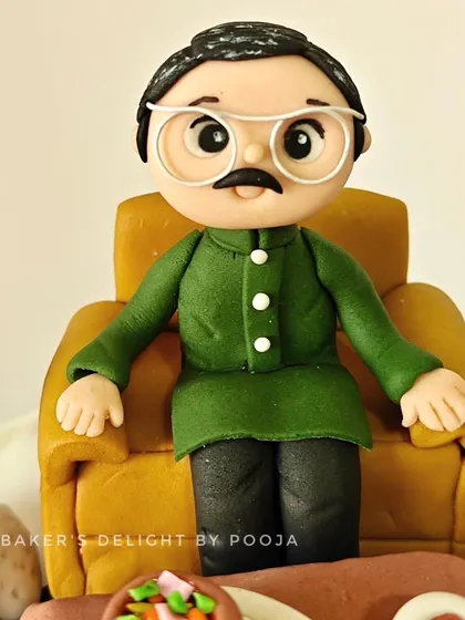 The handcrafted human figurine for the 60th birthday cake, designed to closely resemble the client's father, right down to his green kurta and glasses.