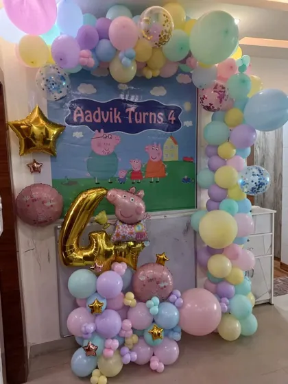 A Peppa Pig themed birthday decoration for a 4-year-old. I used pastel balloons to create an arch around a Peppa Pig backdrop, along with a large number '4' foil balloon.