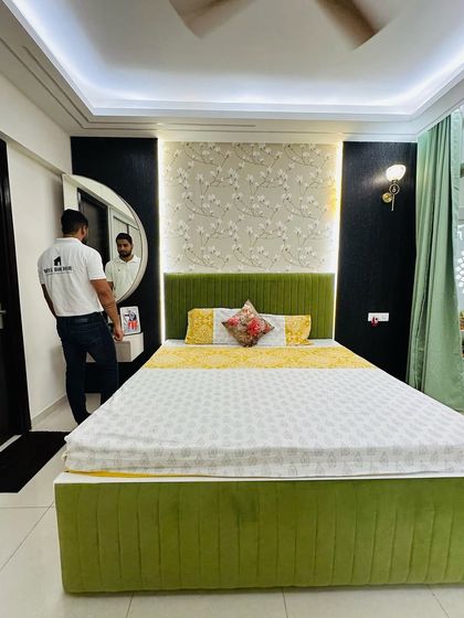 A vibrant guest bedroom with a green upholstered bed and a beautiful floral wallpaper accent wall.