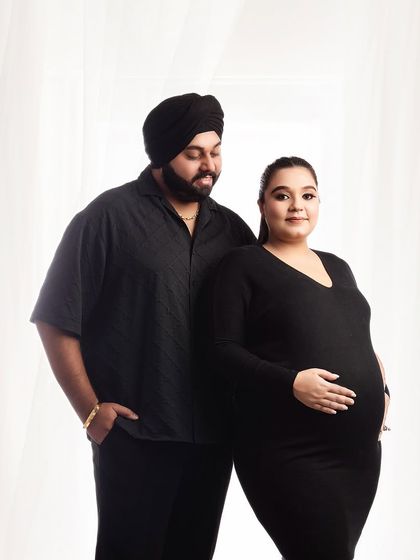 A simple and modern couple portrait in matching black outfits. The clean background and classic posing create a timeless and stylish image of the parents-to-be.