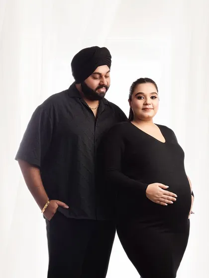 A simple and modern couple portrait in matching black outfits. The clean background and classic posing create a timeless and stylish image of the parents-to-be.
