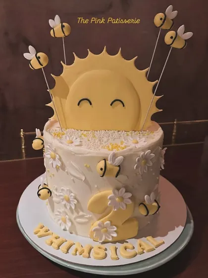 A cheerful "Whimsical" sunshine and bees cake. This design is perfect for a second birthday, with a happy sun and cute fondant bees buzzing around daisies.