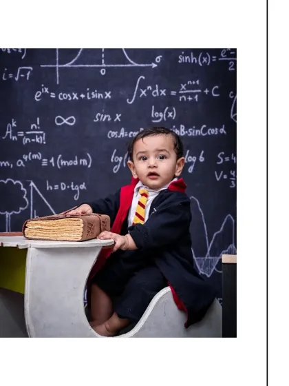 A vertical portrait of the baby wizard looking intently towards the camera. This shot highlights the details of his costume and the intricate chalkboard backdrop.