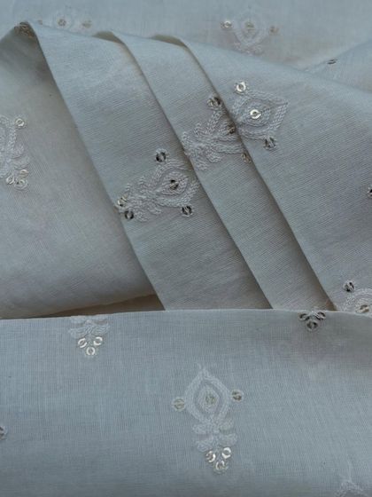 A classic white embroidered cotton with delicate buti and sequin details. This fabric is a timeless choice for creating elegant and comfortable ethnic wear.