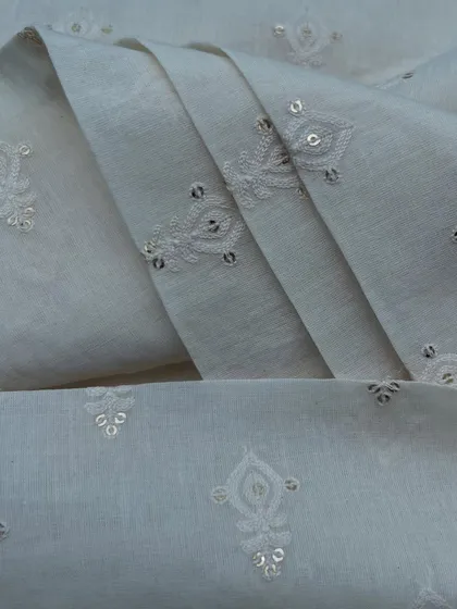 A classic white embroidered cotton with delicate buti and sequin details. This fabric is a timeless choice for creating elegant and comfortable ethnic wear.