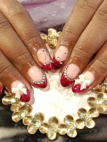 A festive red French manicure taken to the next level with 3D white bows and a border of sparkling rhinestones along the cuticle.
