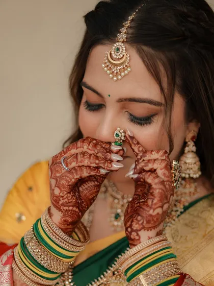 A close-up of the bride adjusting her nose ring, highlighting her intricate henna.