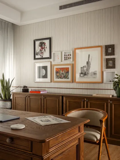 A gallery wall of personal art and photographs makes the study feel curated and lived-in. The credenza provides ample storage, keeping the desktop clear.